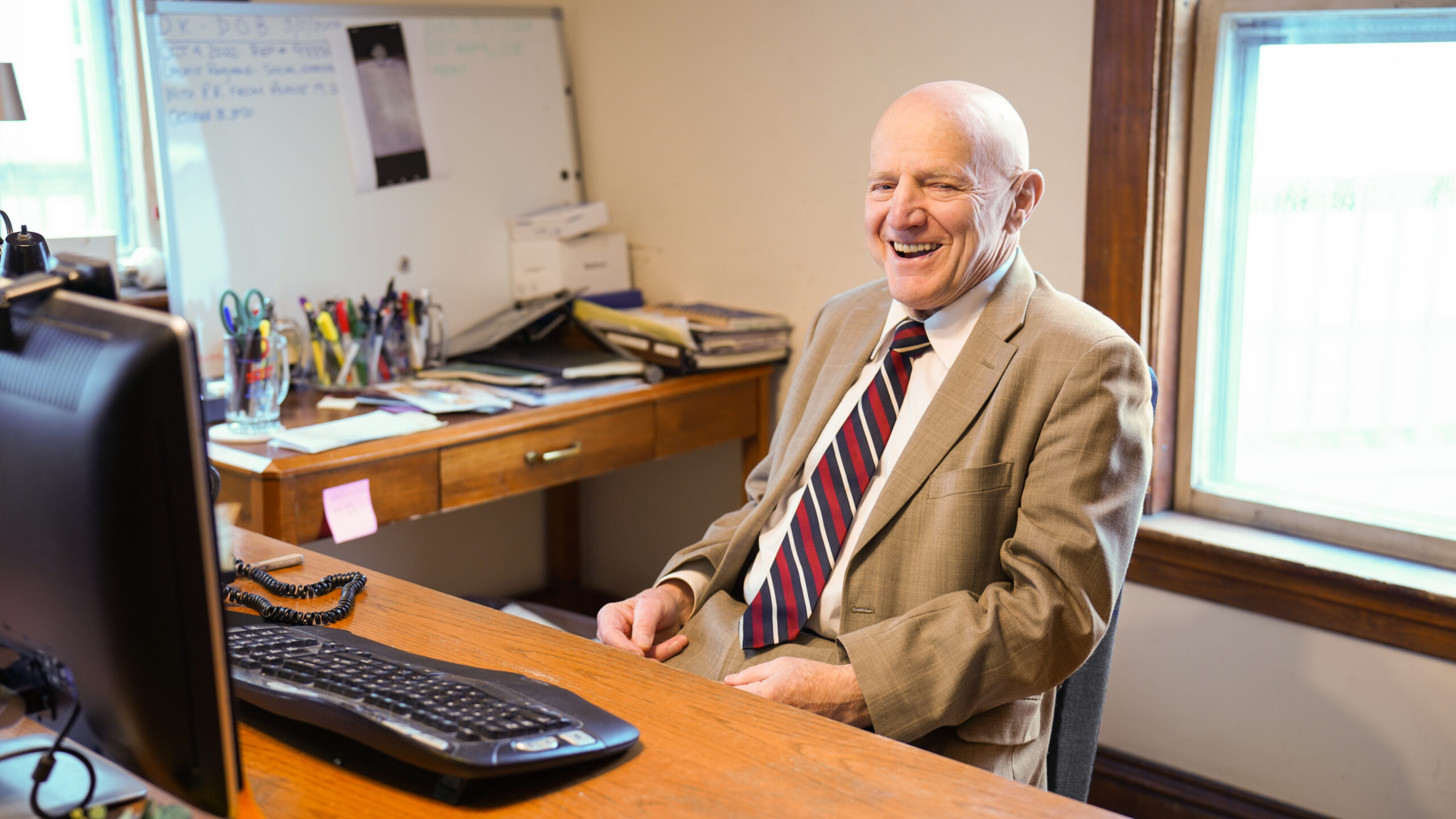 A group of four professionals, two men and two women, are gathered around a conference table reviewing printed charts and documents.