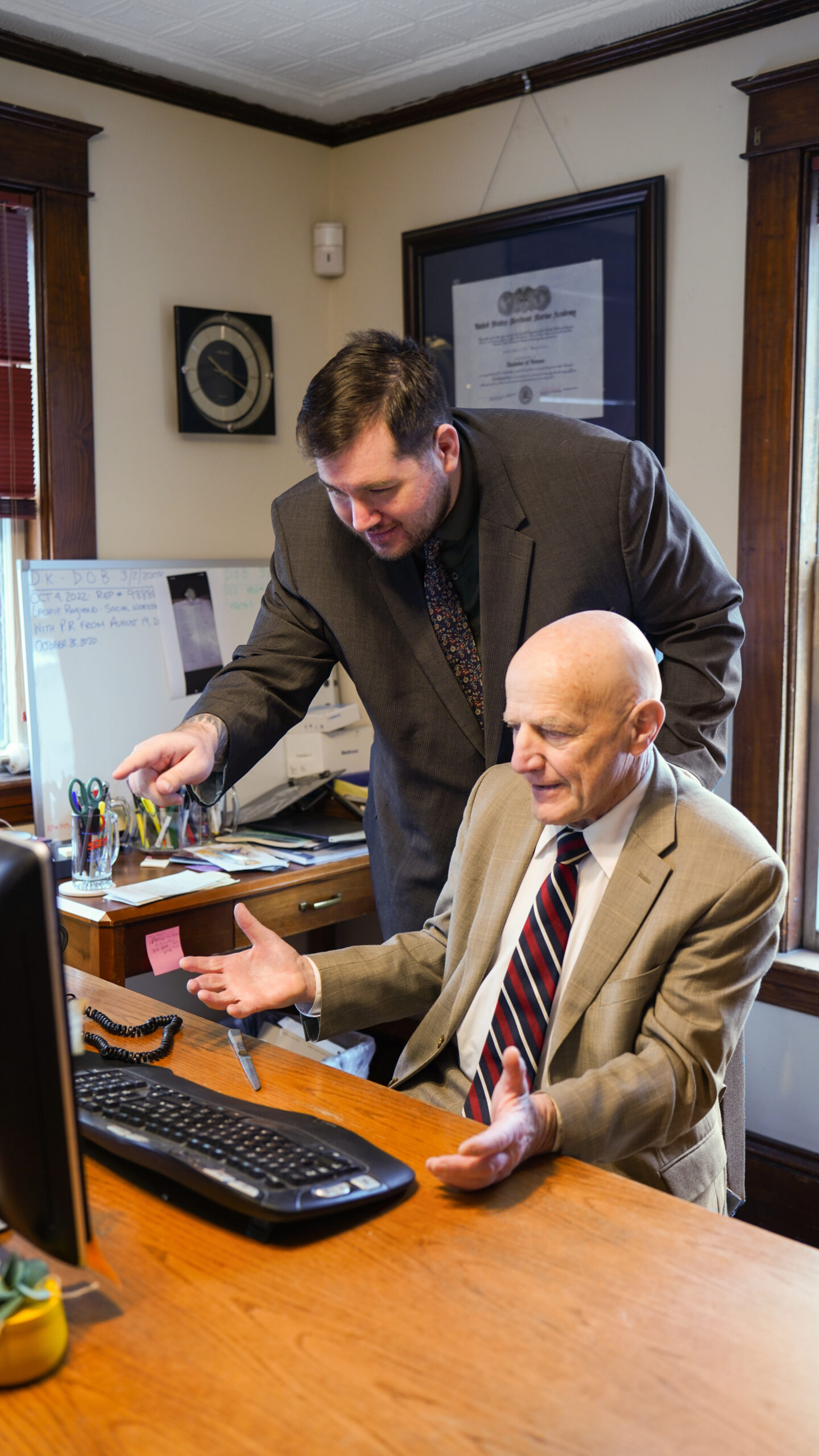 A group of four professionals, two men and two women, are gathered around a conference table reviewing printed charts and documents.