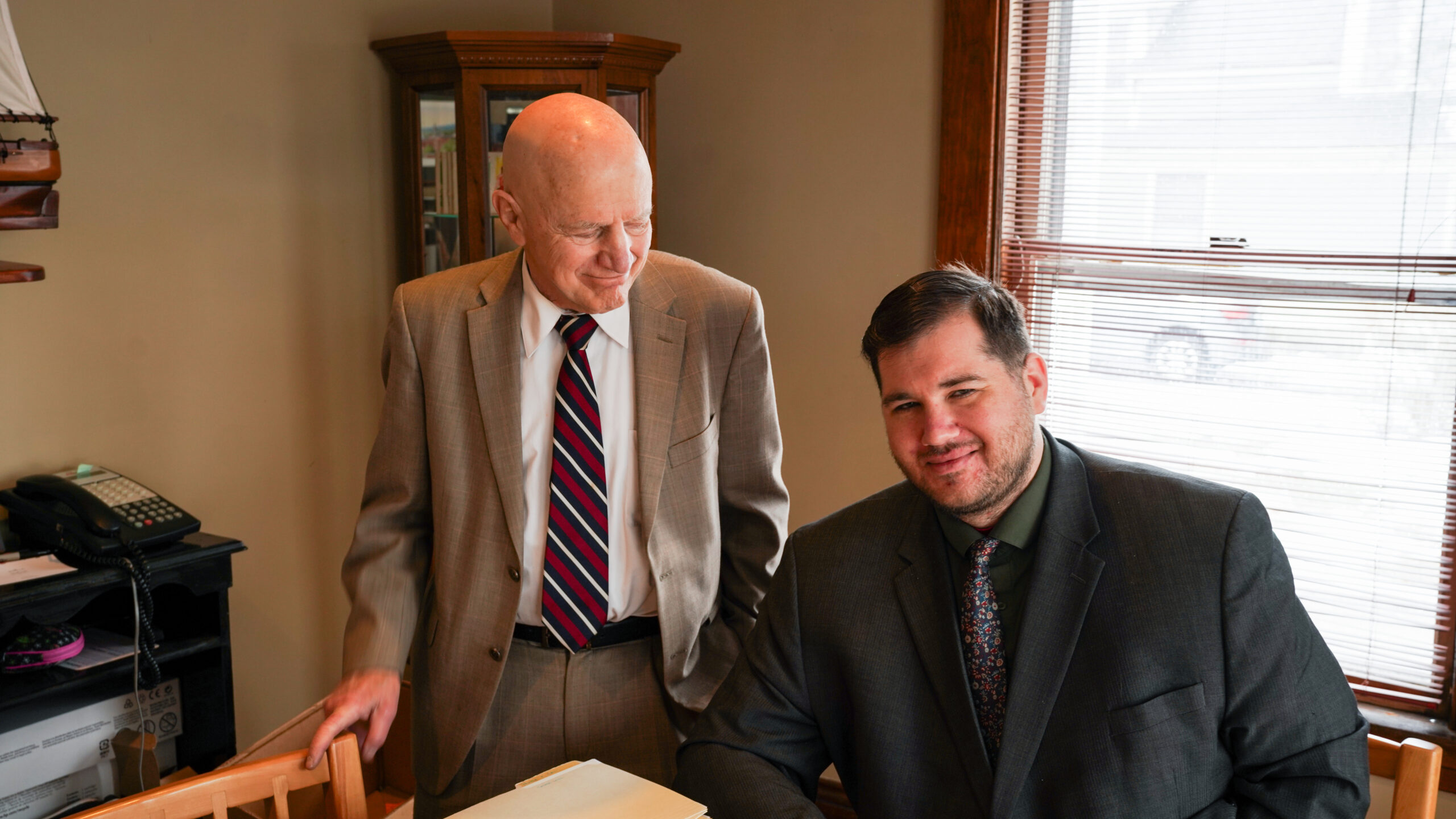 A group of four professionals, two men and two women, are gathered around a conference table reviewing printed charts and documents.