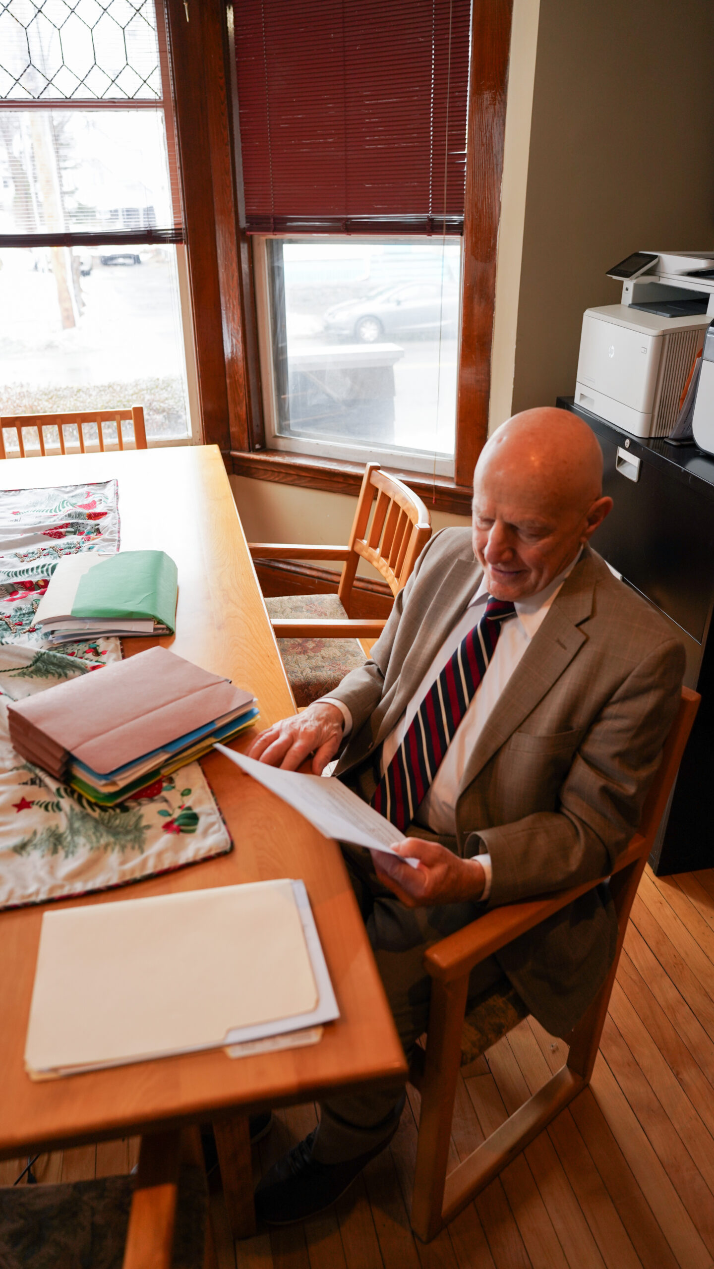 A group of four professionals, two men and two women, are gathered around a conference table reviewing printed charts and documents.