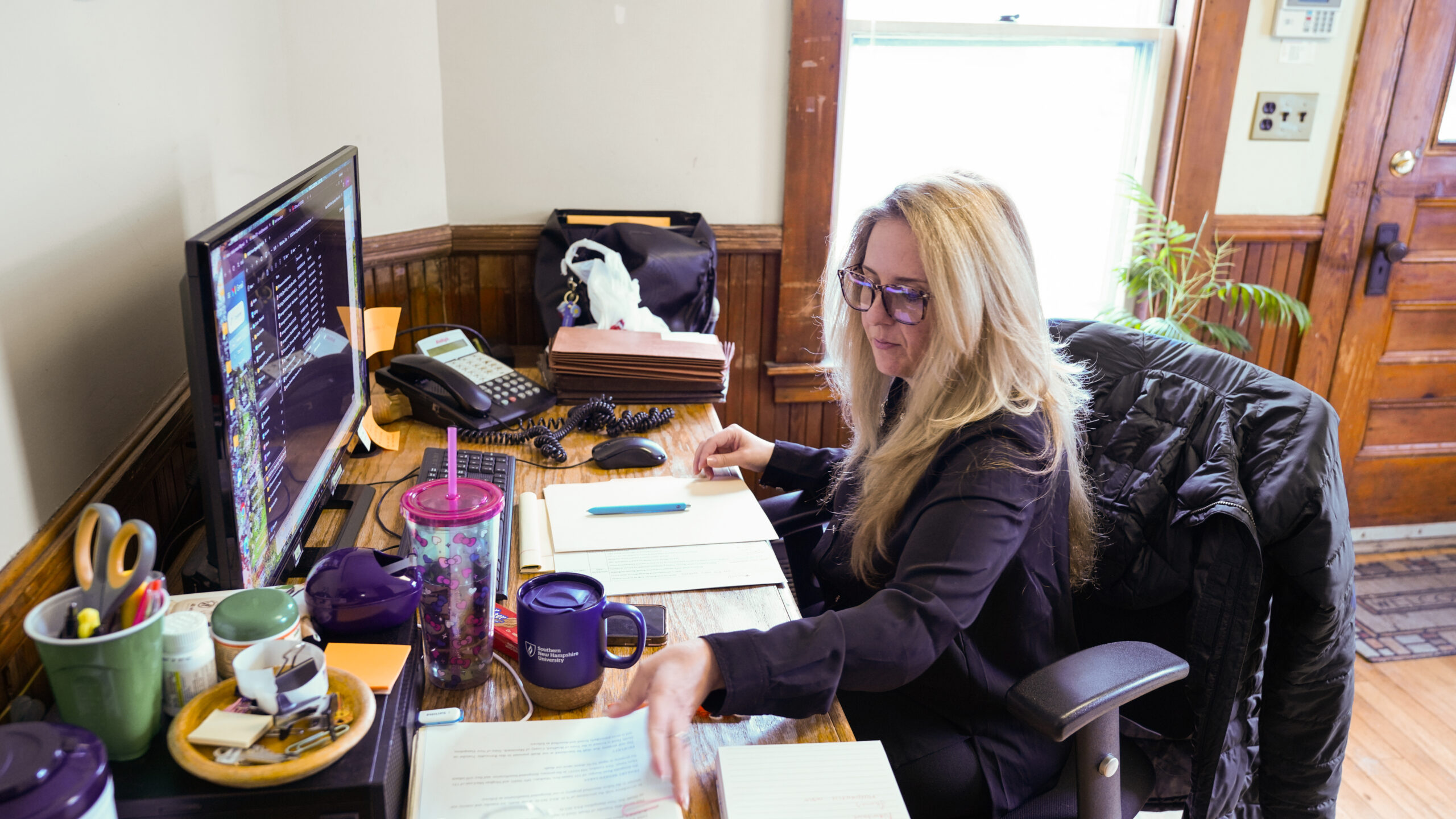 A group of four professionals, two men and two women, are gathered around a conference table reviewing printed charts and documents.