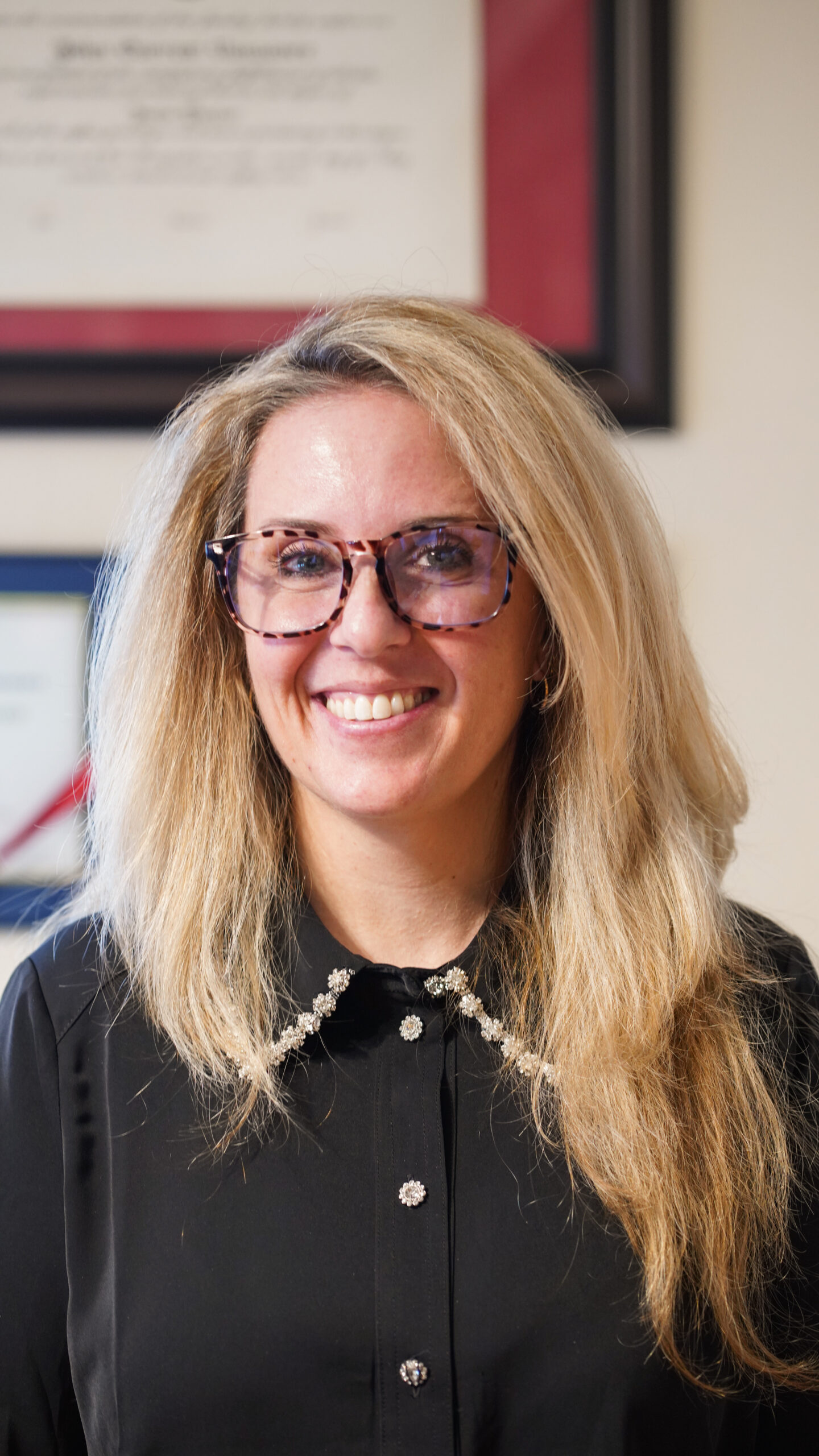 A group of four professionals, two men and two women, are gathered around a conference table reviewing printed charts and documents.