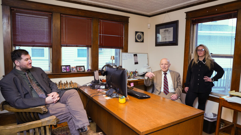 Two young professionals working together at a desk with multiple laptops and a tablet