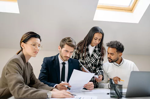 A diverse group of four professionals collaborating at a desk in a modern office.