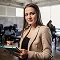 Professional woman holding a tablet, smiling in a modern office setting