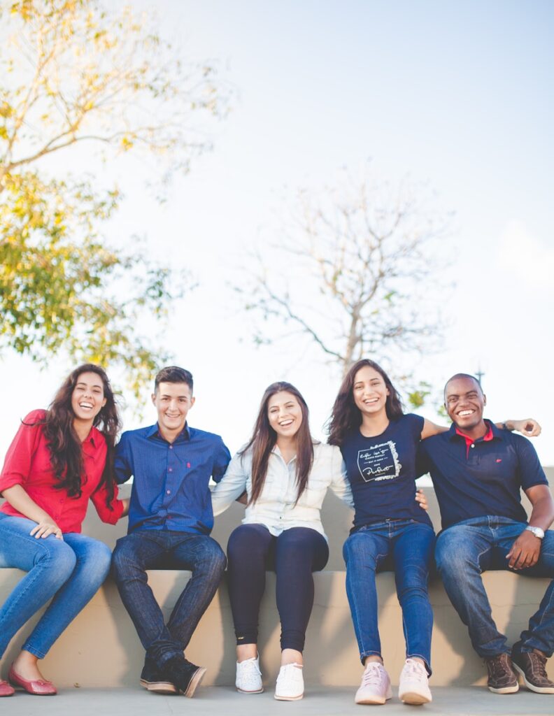 group of people sitting representative of foreign students studying in the United States on student visas, on bench near trees during daytime